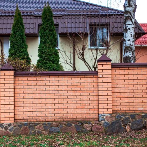 House with a brick fence and tall trees