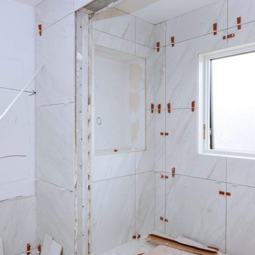 Work laying tile before applying tiles on bathroom tile.